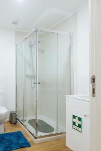 a glass shower in a bathroom with a blue rug at Diogo's Alcântara Apartment II by Mycelia in Lisbon +56 photos