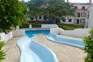 a swimming pool with a blue water slide at Apartamento en Cala en Porter Menorca in Cala'n Porter