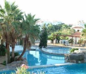 a swimming pool with palm trees in a resort at Apartamento en Cala en Porter Menorca in Cala'n Porter