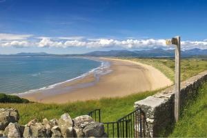 a view of a beach with a stone wall at Artro Lodge Luxury 3 Bedroom, 3 Bathroom & Hot Tub in Llanbedr