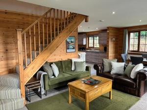 a living room with a couch and a staircase at Artro Lodge Luxury 3 Bedroom, 3 Bathroom & Hot Tub in Llanbedr