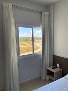 Schlafzimmer mit einem Fenster mit Blick auf ein Feld in der Unterkunft Apartamento Lagoa Ecotowers resort in Caldas Novas