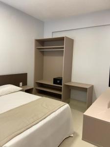 ein Schlafzimmer mit einem Bett, einem Schreibtisch und einem Regal in der Unterkunft Apartamento Lagoa Ecotowers resort in Caldas Novas