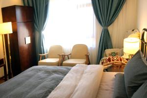 a hotel room with a bed and chairs and a window at La Maison du Laoshay Lijiang in Lijiang