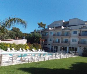 um grande edifício com piscina e cadeiras em Álamos del Mar Apart Hotel & Spa em Valeria del Mar
