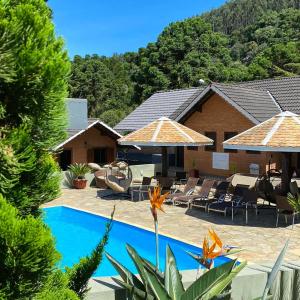 um resort com uma piscina com cadeiras e guarda-sóis em Pousada Serras De Monte Verde em Monte Verde