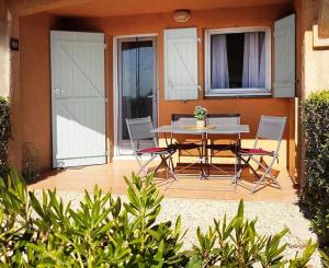 eine Terrasse mit einem Tisch und Stühlen sowie ein Haus in der Unterkunft Le Petit Bonheur - Location de vacances (Studio 4P) in Roquebrune-sur-Argens