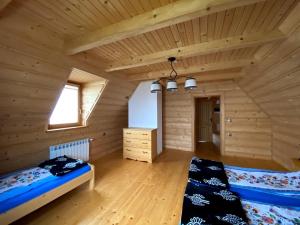 ein Schlafzimmer in einem Blockhaus mit einem Bett und einem Fenster in der Unterkunft Dom z widokiem na Wierchy. Traditional folk house in Gliczarów Górny