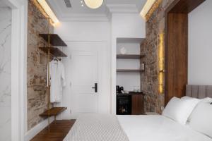 a bedroom with a white bed and a brick wall at La Divina in Athens