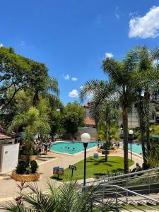 une piscine avec des palmiers et des personnes dans un parc dans l'établissement Casa dos Gerânios com Piscina - Próximo ao Parque Termal!, à Piratuba