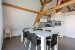 kuchnia i jadalnia z białym stołem i krzesłami w obiekcie Spacious holiday home with indoor pool & sauna w mieście Veurne