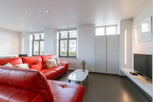 a living room with a red couch and a tv at Spacious holiday home with indoor pool & sauna in Veurne