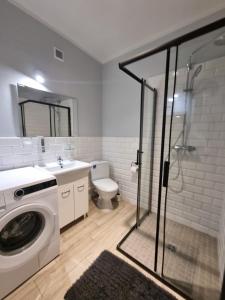 La salle de bains est pourvue d'un lave-linge et de toilettes. dans l'établissement Apartamenty Firfas 9, à Bydgoszcz