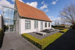 Biały budynek z dwoma ławkami przed nim w obiekcie Spacious holiday home with indoor pool & sauna w mieście Veurne