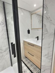 uma casa de banho branca com um lavatório e um chuveiro em Suite bien être - jacuzzi et sauna / love room em Arpajon