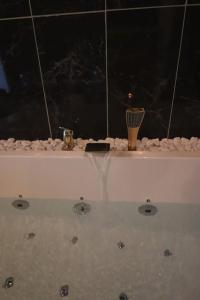 アルパジョンにあるSuite bien être - jacuzzi et sauna / love roomの白いバスタブ(水中の排水口3つ付)