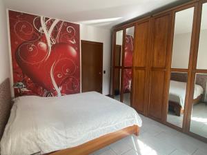 1 dormitorio con cama y pared roja en IL GIARDINO DI ZEUS, en Cologno Monzese