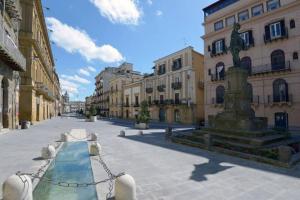 a street with a fountain in the middle of a building at Appartamento con piscina per 4 persone in San Cataldo