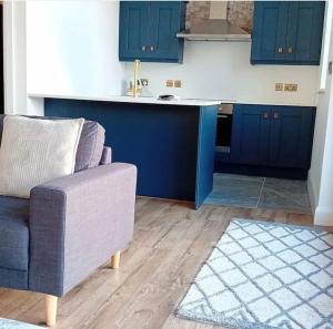 a kitchen with blue cabinets and a couch and a sink at Silver Strand Lodge in Glencolumbkille