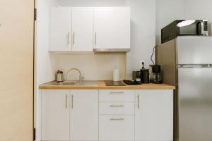 a white kitchen with a sink and a refrigerator at Snug studio apartment with pvt garden access I in Athens