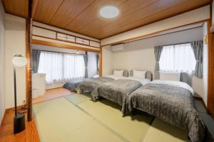 twee bedden in een kamer met ramen bij LINKAGE STAY HAKONE SENGOKUHARA in Hakone