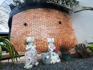 deux chats en peluche assis à côté d'un mur de briques dans l'établissement D'Cove Villa Private Pool Kuantan, à Kuantan 36 autres photos
