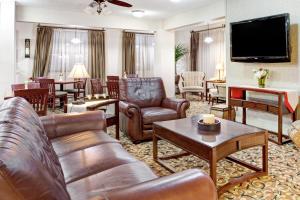 sala de estar con muebles de cuero y TV de pantalla plana en Ramada by Wyndham West Memphis en West Memphis