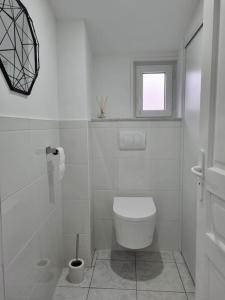 a white bathroom with a toilet and a window at Gîte moderne, tout confort avec extérieur in Givenchy-en-Gohelle