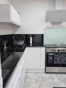 a kitchen with white cabinets and a stove top oven at Gîte moderne, tout confort avec extérieur in Givenchy-en-Gohelle