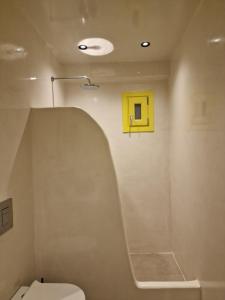 a bathroom with a toilet and a yellow box on the wall at New Earth in Kamari