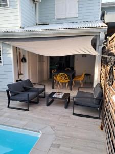un patio con sofás, una mesa y una piscina en Villa Mahi Mahi, en Les Trois-Îlets