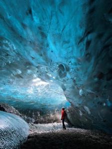 a person standing in front of an ice cave at Vagnsstadir Guesthouse in Borgarhöfn