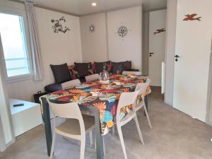 ein Esszimmer mit einem Tisch mit Stühlen und einem Sofa in der Unterkunft Chalet 2 Chambres à Labouheyre avec Piscine Chauffée, WiFi et Terrasse au Bord d'un Lac - FR-1-783-25 in Labouheyre