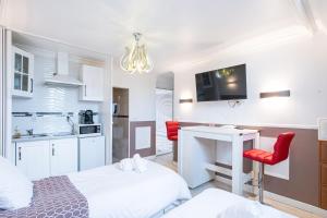 a room with two beds and a desk and a kitchen at Studio Marron - Paris à 10 min - RER in Deuil-la-Barre