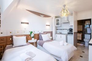 twee bedden in een kleine kamer met een keuken bij Studio Marron - Paris à 10 min - RER in Deuil-la-Barre