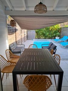 un patio con mesa, sillas y piscina en Villa Mahi Mahi, en Les Trois-Îlets