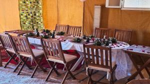een eetkamer met een tafel met houten stoelen bij Nejma luxury camp erg chegaga in El Gouera