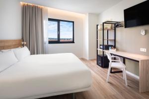 エシハにあるB&B HOTEL Écijaのベッドとデスクが備わるホテルルームです。