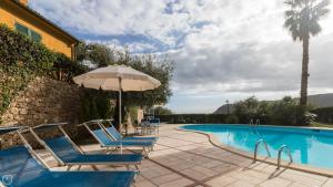 een zwembad met blauwe stoelen en een parasol bij Italianway - Il Borgo apartments in Finale Ligure