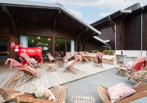 une terrasse en bois avec des chaises et une statue d'une vache dans l'établissement Mamie Megève, à Megève