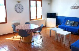 uma sala de estar com mesa e cadeiras e um relógio em La Tour Fondue Appartement vue mer Grand T2 face a Porquerolles Drap serviette non fournis em Hyères