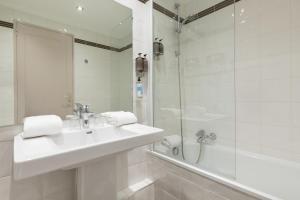ein weißes Bad mit einem Waschbecken und einer Dusche in der Unterkunft Hôtel Charlemagne by Happyculture in Lyon