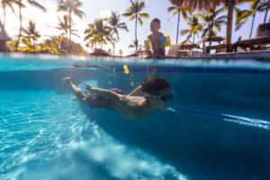 a young child swimming in a swimming pool at OUTRIGGER Kona Resort and Spa in Kailua-Kona