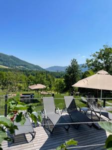 a deck with two chairs and an umbrella at Hotel Hemetsberger in Attersee am Attersee