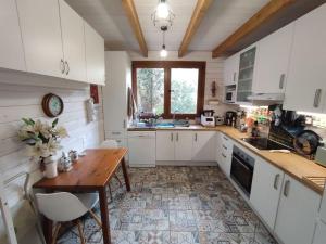 a kitchen with white cabinets and a wooden table at Preciosa cabaña con jardín y barbacoa in Guadarrama