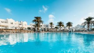 una gran piscina con palmeras y edificios blancos en Labranda Corralejo Village, en Corralejo