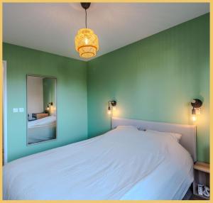 - une chambre avec un lit blanc et un miroir dans l'établissement Chez Clemence T3 Ville La Grand, à Ville-la-Grand