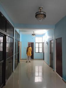 a man in a yellow raincoat standing in a hallway at Jankivihar Homestay at Prahladghat within 1km from Shri Ram Mandir in Ayodhya