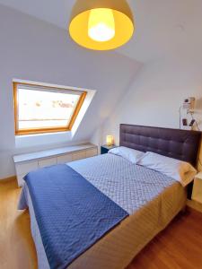 a bedroom with a bed with a blue comforter and a window at Vivienda Novo Betanzos in Betanzos