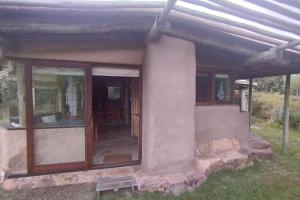 een klein huis met ramen en een bank buiten bij Casas de barro Altamira del Eden. in El Eden